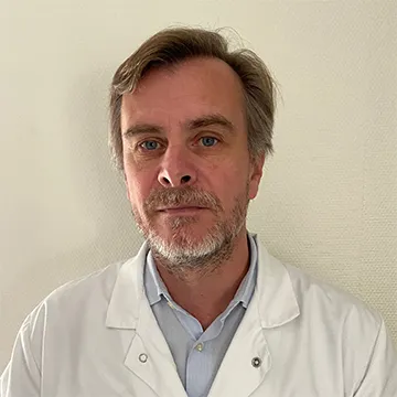 Portrait du Professeur Sébastien Froelich en blouse médicale blanche.